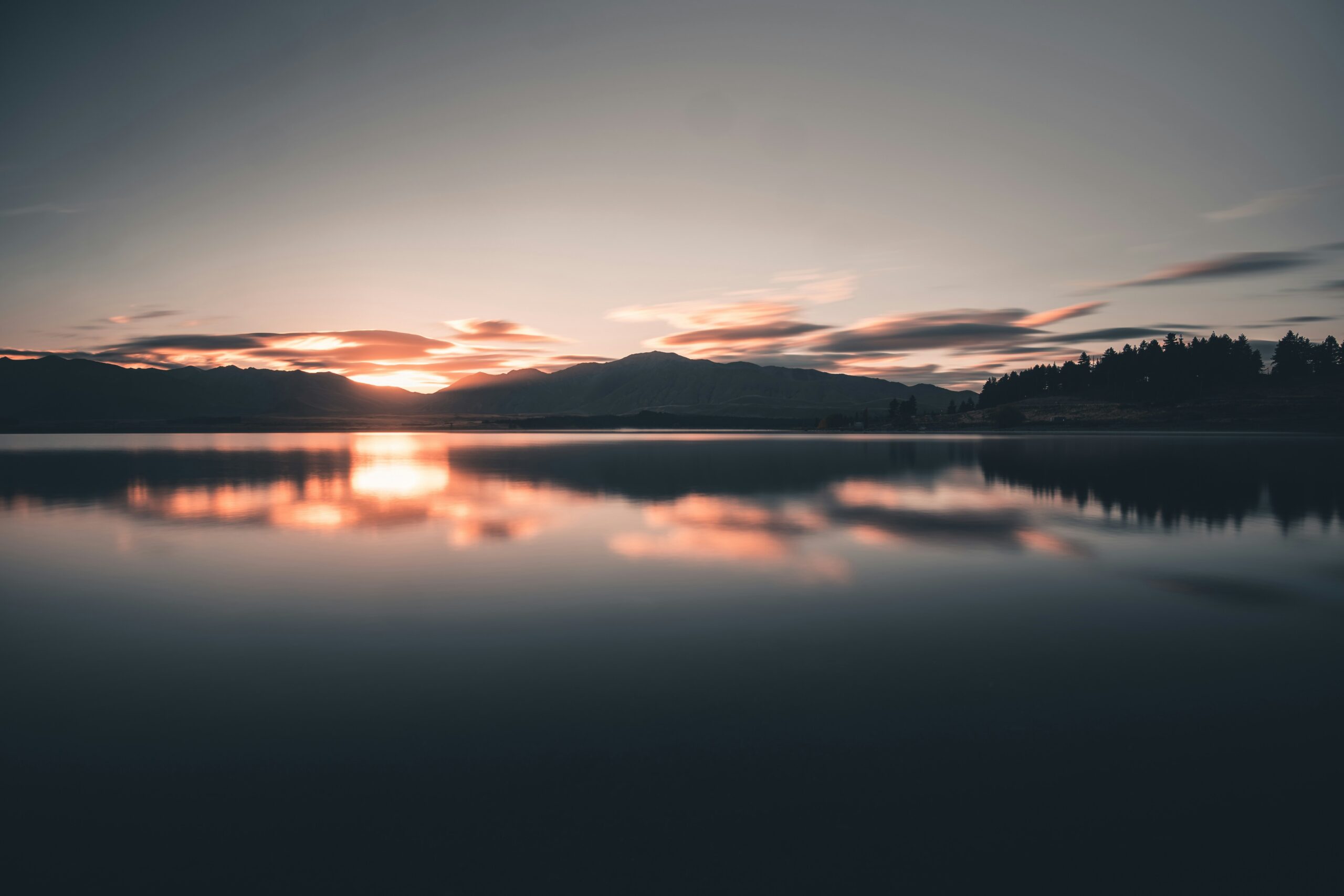 Woman meditating by serene lake during sunrise