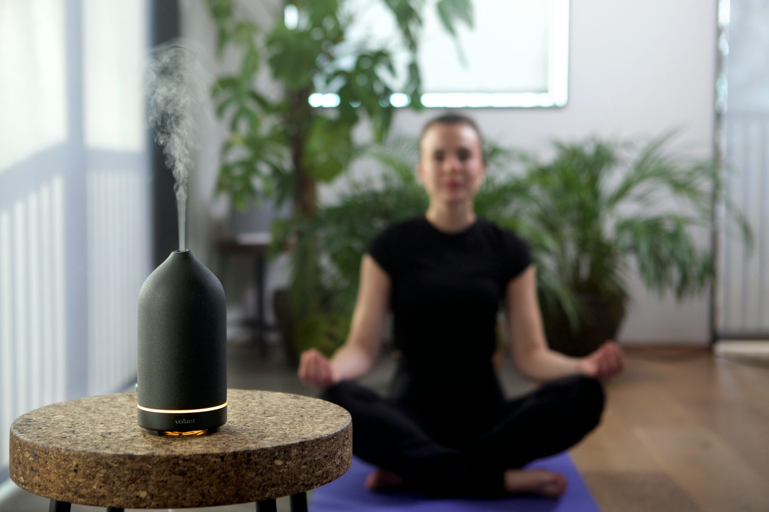 Woman combining yoga and aromatherapy with a black volant diffuser helps support physical and spiritual well-being.
