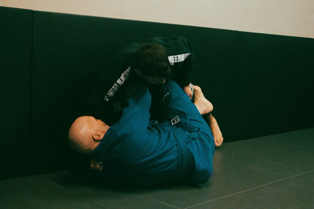 a man in a blue shirt is wrestling another man in a black shirt